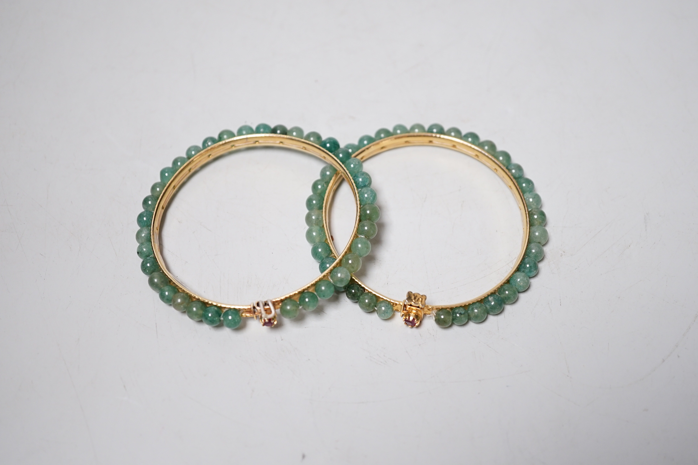 A pair of yellow metal and jade bangles, 7.2cm diameter